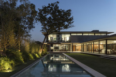 La vivienda Garafulic consta con un terreno privilegiado rodeado de vegetación que está situado en una urbanización cerrada en la zona del Urubó. La topografía natural del terreno permite que la volumetría de la casa se apoye en el punto más alto del mismo, aprovechando así los desniveles para poder generar una planta de servicio en el subsuelo. Esto nos permite resolver el programa de la vivienda en 3 niveles, pero al mismo tiempo mantener una composición de dos volúmenes que se solapan y se posan sobre el terreno natural.

El acceso principal nos dirige hacia la planta baja, la que está resuelta bajo el concepto de `planta libre´. Diferentes áreas de servicio como el sauna, la escalera principal,  el shaft, la despensa y  la vinoteca; funcionan como volúmenes de separación y actúan como colchones entre los distintos programas. Con el fin de no generar habitaciones cerradas, la planta baja genera un espacio en común cuyas divisiones crean una fragmentación del espacio entre los distintos programas sin afectar la circulación libre

El recibidor o hall funciona como un distribuidor entre el family room y el pasillo principal, que nos lleva al cuarto de huéspedes, la cocina o el living comedor.  Entre el living-comedor y el gimnasio podemos apreciar una galería que nos lleva a una cubierta verde que mira hacia el patio interior y la piscina.

En el segundo piso contamos con el estar familiar y dos habitaciones en suite. La habitación principal cuenta con una pequeña terraza que aprovecha las mejores vistas del terreno hacia un pequeño bosque localizado al frente del mismo.