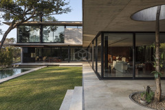 La vivienda Garafulic consta con un terreno privilegiado rodeado de vegetación que está situado en una urbanización cerrada en la zona del Urubó. La topografía natural del terreno permite que la volumetría de la casa se apoye en el punto más alto del mismo, aprovechando así los desniveles para poder generar una planta de servicio en el subsuelo. Esto nos permite resolver el programa de la vivienda en 3 niveles, pero al mismo tiempo mantener una composición de dos volúmenes que se solapan y se posan sobre el terreno natural.

El acceso principal nos dirige hacia la planta baja, la que está resuelta bajo el concepto de `planta libre´. Diferentes áreas de servicio como el sauna, la escalera principal,  el shaft, la despensa y  la vinoteca; funcionan como volúmenes de separación y actúan como colchones entre los distintos programas. Con el fin de no generar habitaciones cerradas, la planta baja genera un espacio en común cuyas divisiones crean una fragmentación del espacio entre los distintos programas sin afectar la circulación libre

El recibidor o hall funciona como un distribuidor entre el family room y el pasillo principal, que nos lleva al cuarto de huéspedes, la cocina o el living comedor.  Entre el living-comedor y el gimnasio podemos apreciar una galería que nos lleva a una cubierta verde que mira hacia el patio interior y la piscina.

En el segundo piso contamos con el estar familiar y dos habitaciones en suite. La habitación principal cuenta con una pequeña terraza que aprovecha las mejores vistas del terreno hacia un pequeño bosque localizado al frente del mismo.